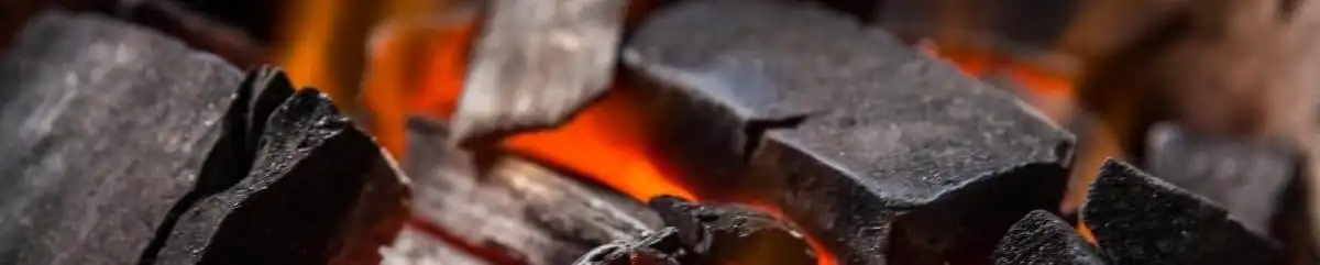 Bara api arang yang menyala merah di dalam sebuah kompor arang, siap untuk membakar sate.