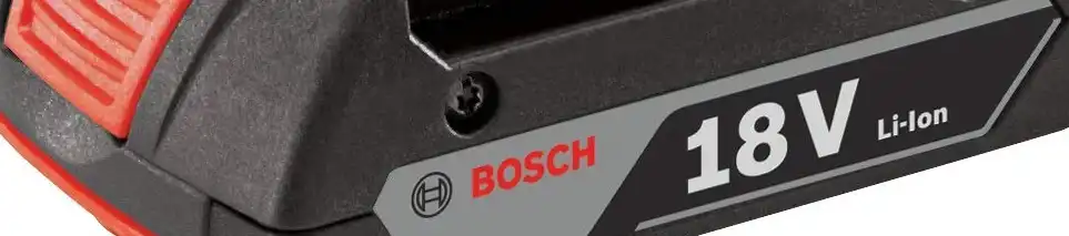 Sebuah bor cordless dipegang dengan fokus pada bagian baterainya.